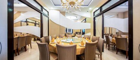 A modern dining area with a round table, multiple chairs, and a chandelier.
