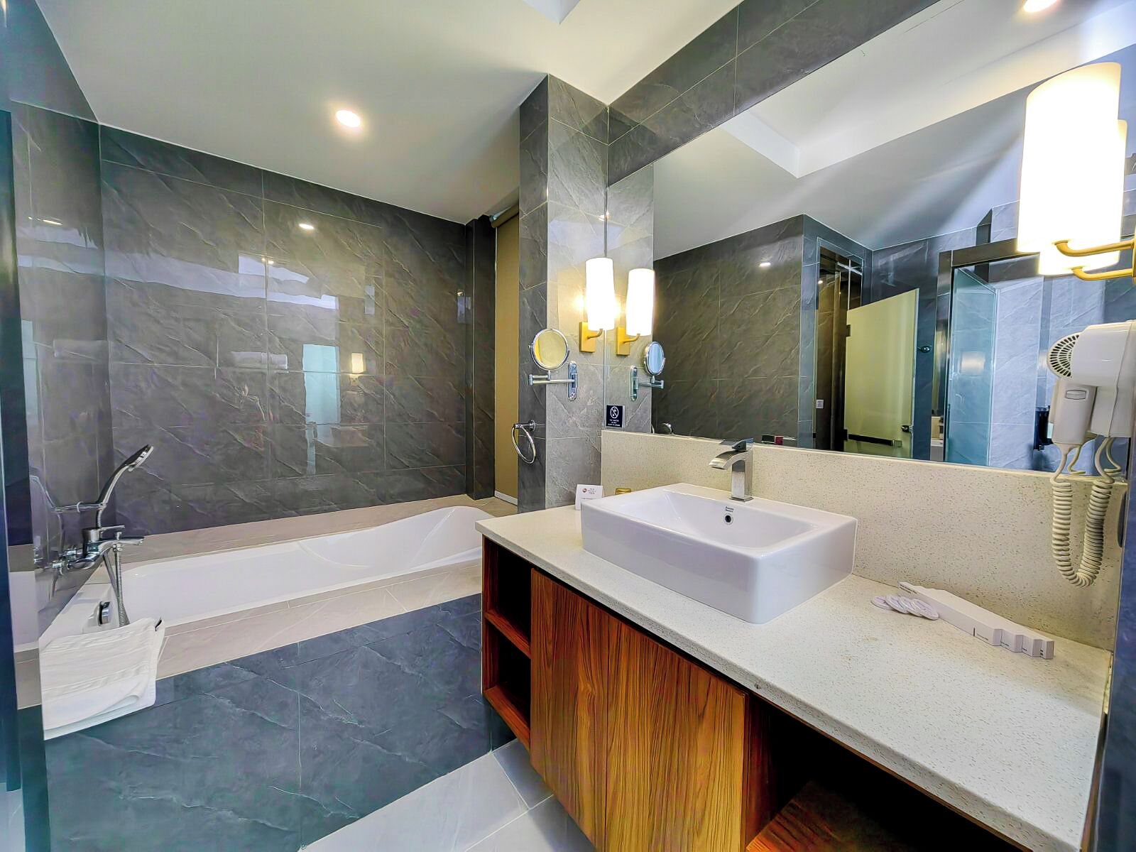 A modern bathroom with a bathtub, a vanity with a sink, and a large mirror.