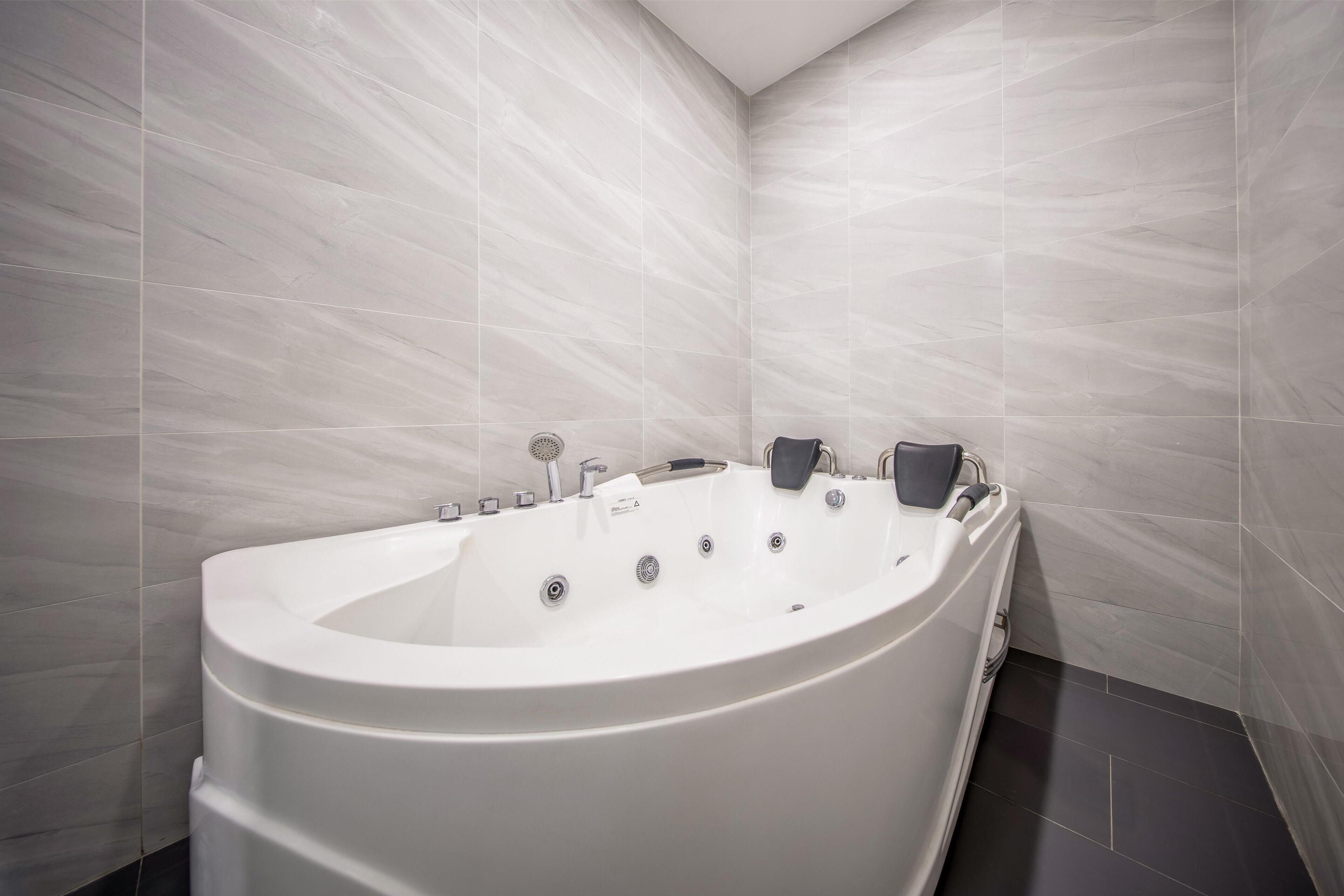 A modern bathroom with a freestanding bathtub, a handheld showerhead, and a wall-mounted faucet.