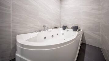 Un baño moderno con una bañera independiente, un cabezal de ducha de mano y un grifo de pared.