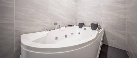 A modern bathroom with a freestanding bathtub, a handheld showerhead, and a wall-mounted faucet.