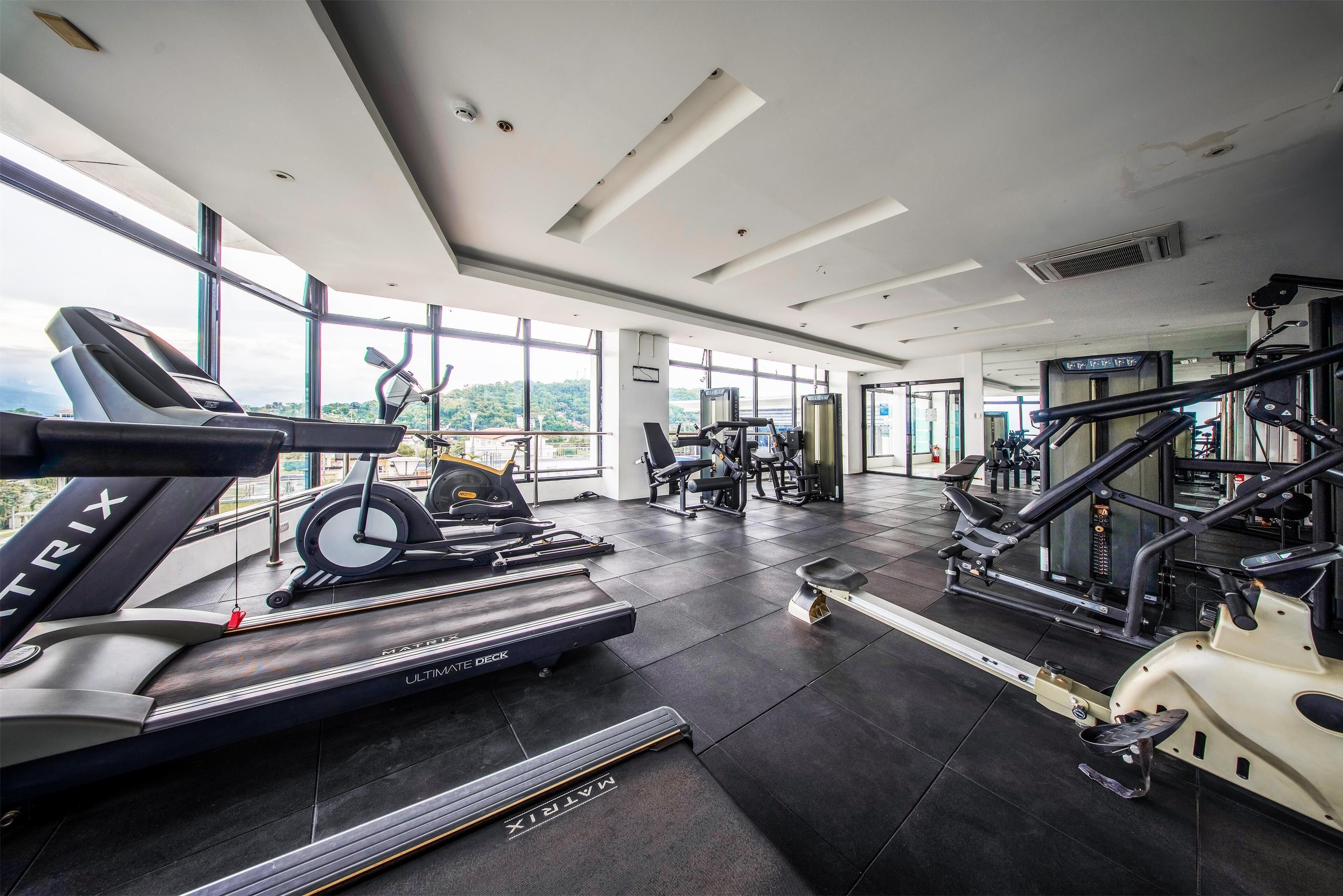 A modern gym with treadmills, elliptical machines, and weightlifting equipment.