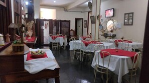 A dining area with multiple tables and chairs, some with red tablecloths. - Pousada Ouro de Minas (Diamantina)