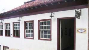 A building with a red-tiled roof, white walls, and multiple windows with red frames.