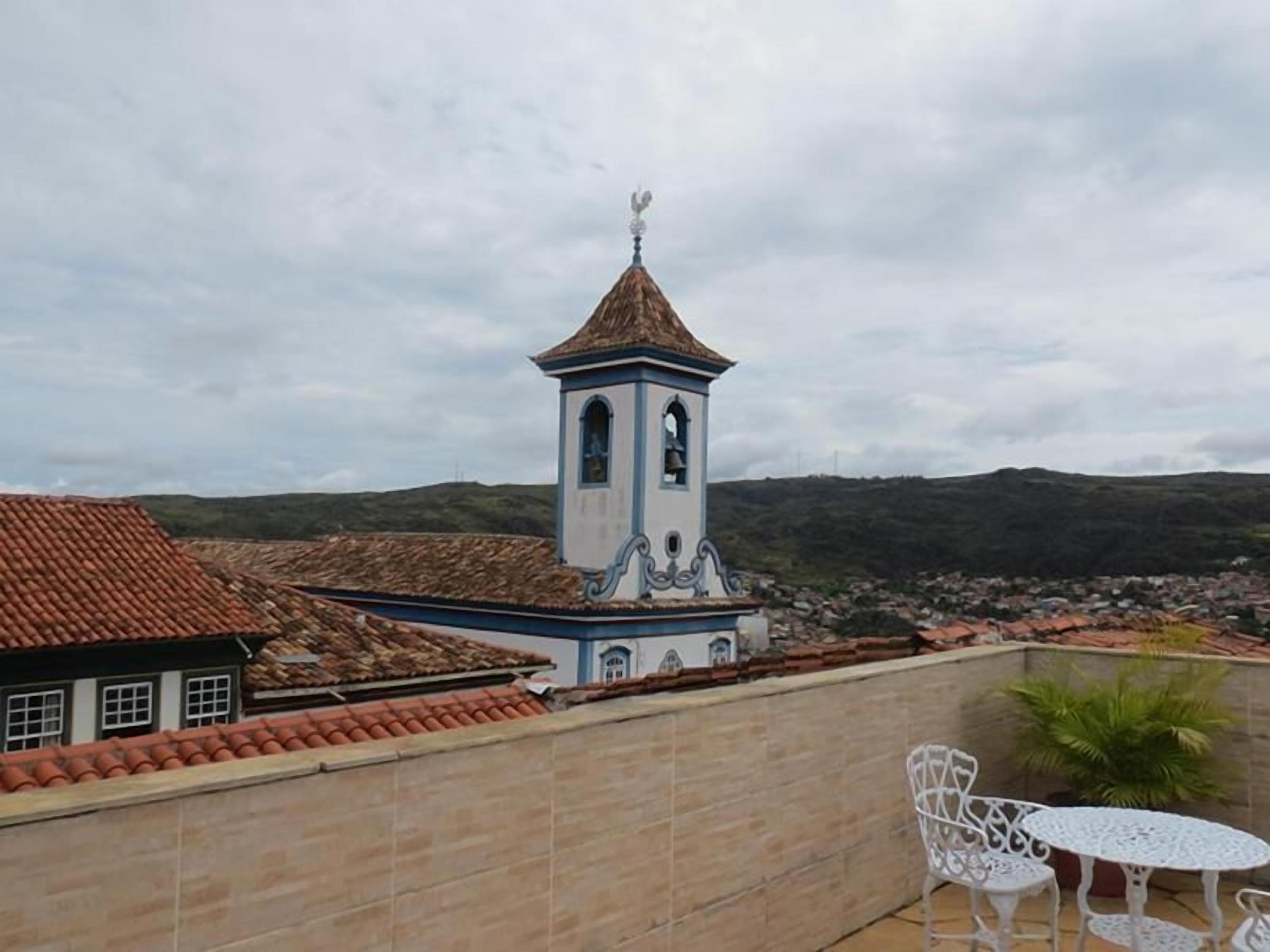 A church with a bell tower, a tiled roof, and a white fence.