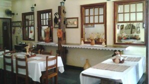 A dining area with tables set for two, wooden chairs, and a counter with decorative items.