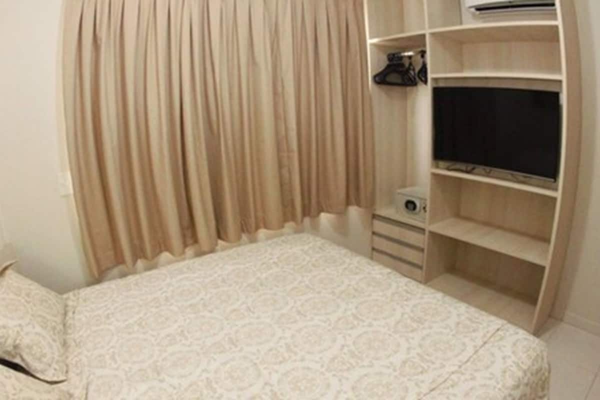 Quarto com cama, guarda-roupa e televisão.