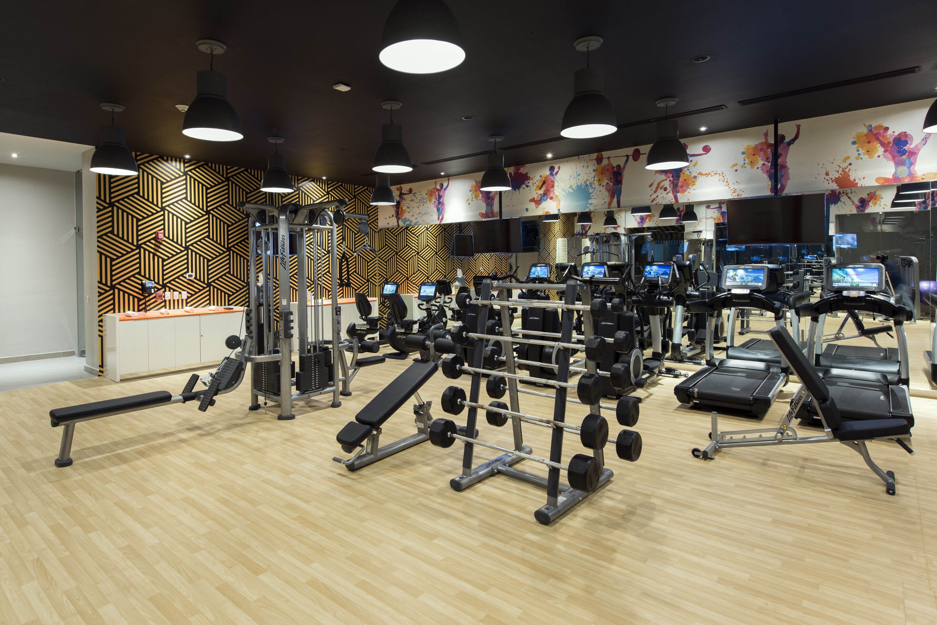 Una palestra moderna con diverse attrezzature per esercizi, tra cui tapis roulant, macchinari per pesi e pesi liberi.