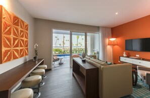 A modern hotel room with a pool view, a bar area, and a seating space with a TV.