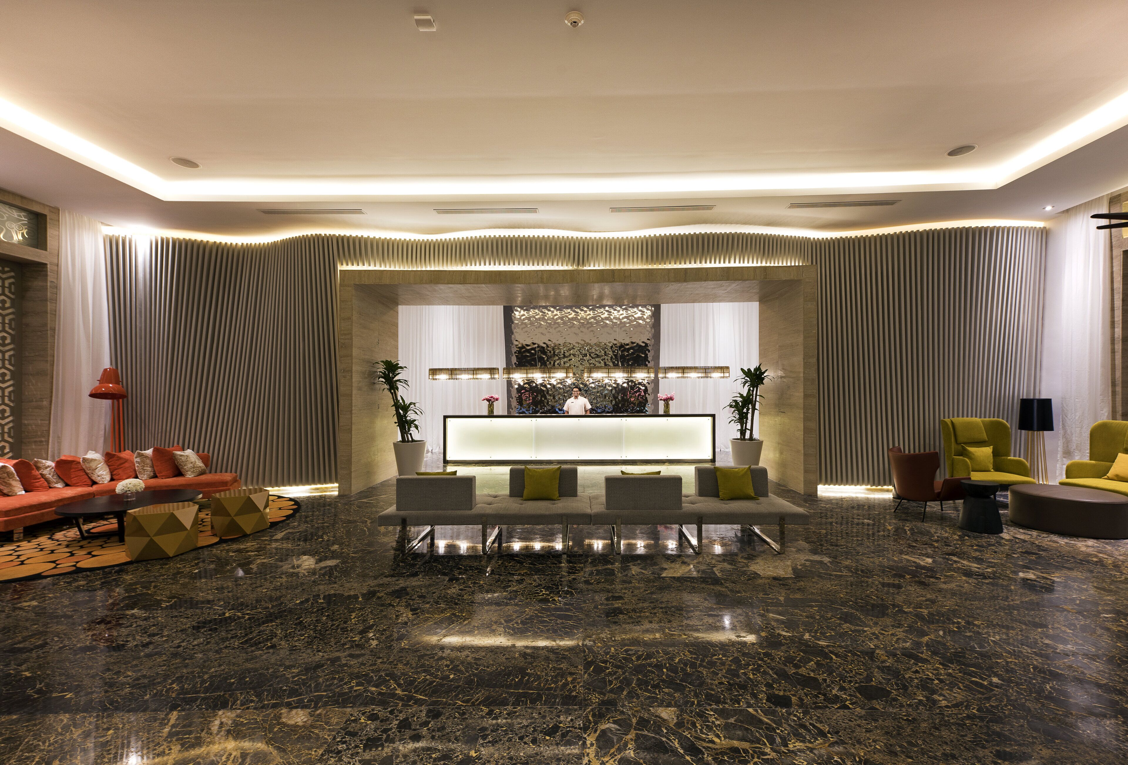 Een moderne lobby met een marmeren vloer, een receptiebalie en zithoeken.