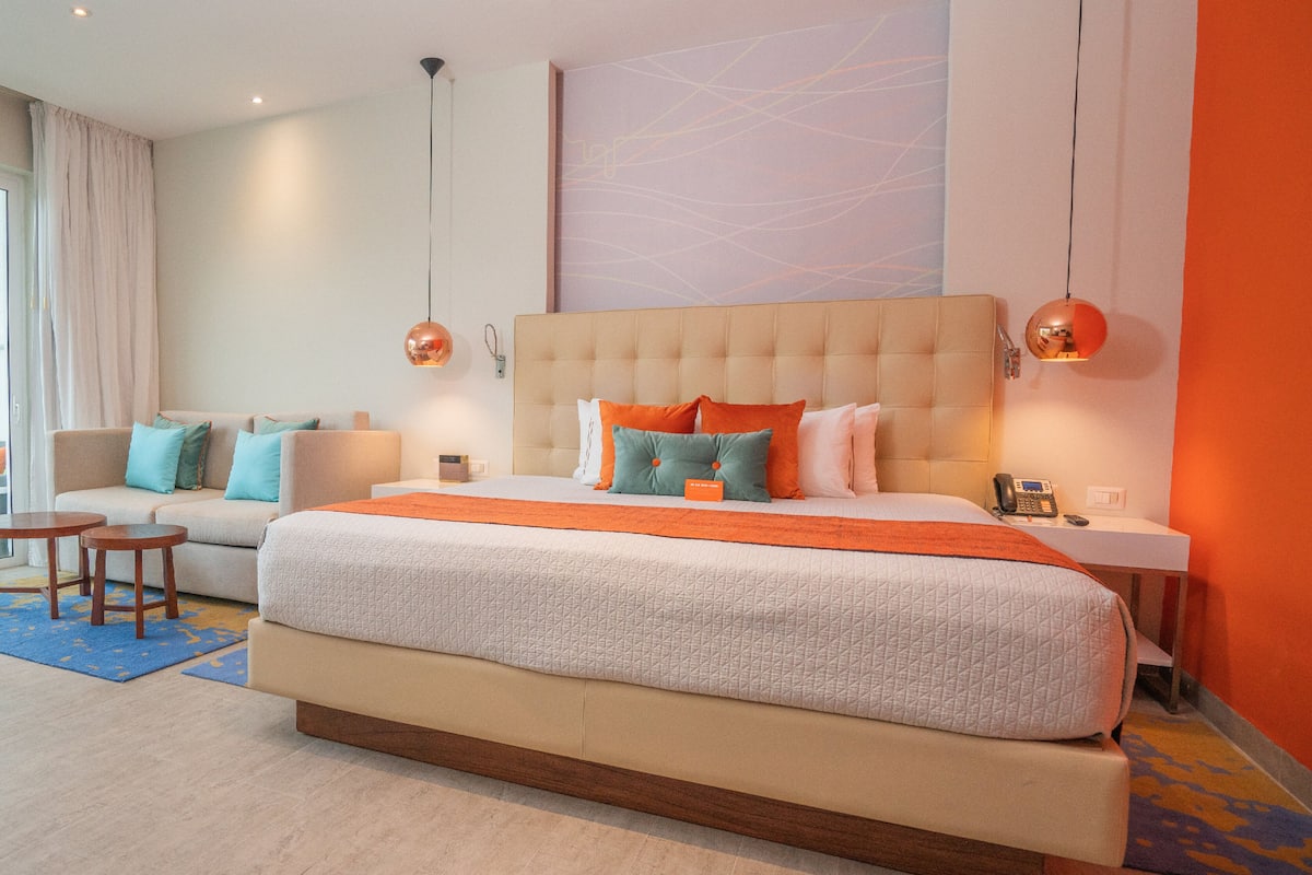 Ein Hotelzimmer mit einem großen Bett, einer Schlafcouch, zwei Beistelltischen und einem Telefon.