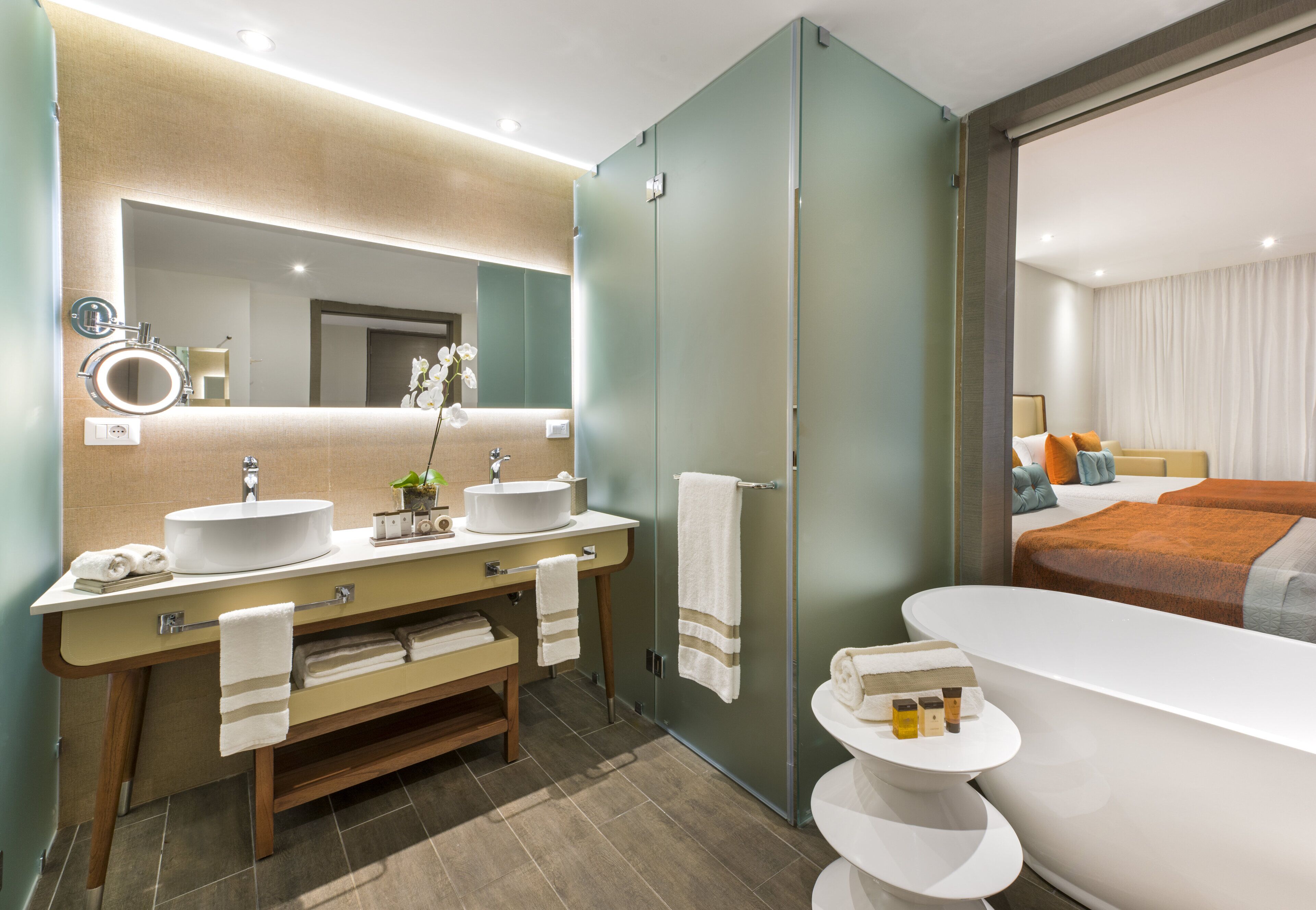 Un baño moderno con un espejo grande, dos lavamanos, un mueble de tocador y una bañera.