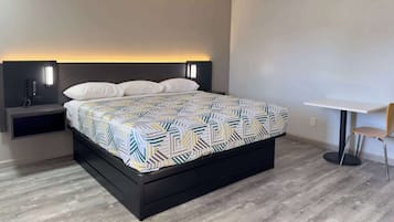 Un dormitorio moderno con una cama, mesitas de noche y una pequeña mesa con una silla.