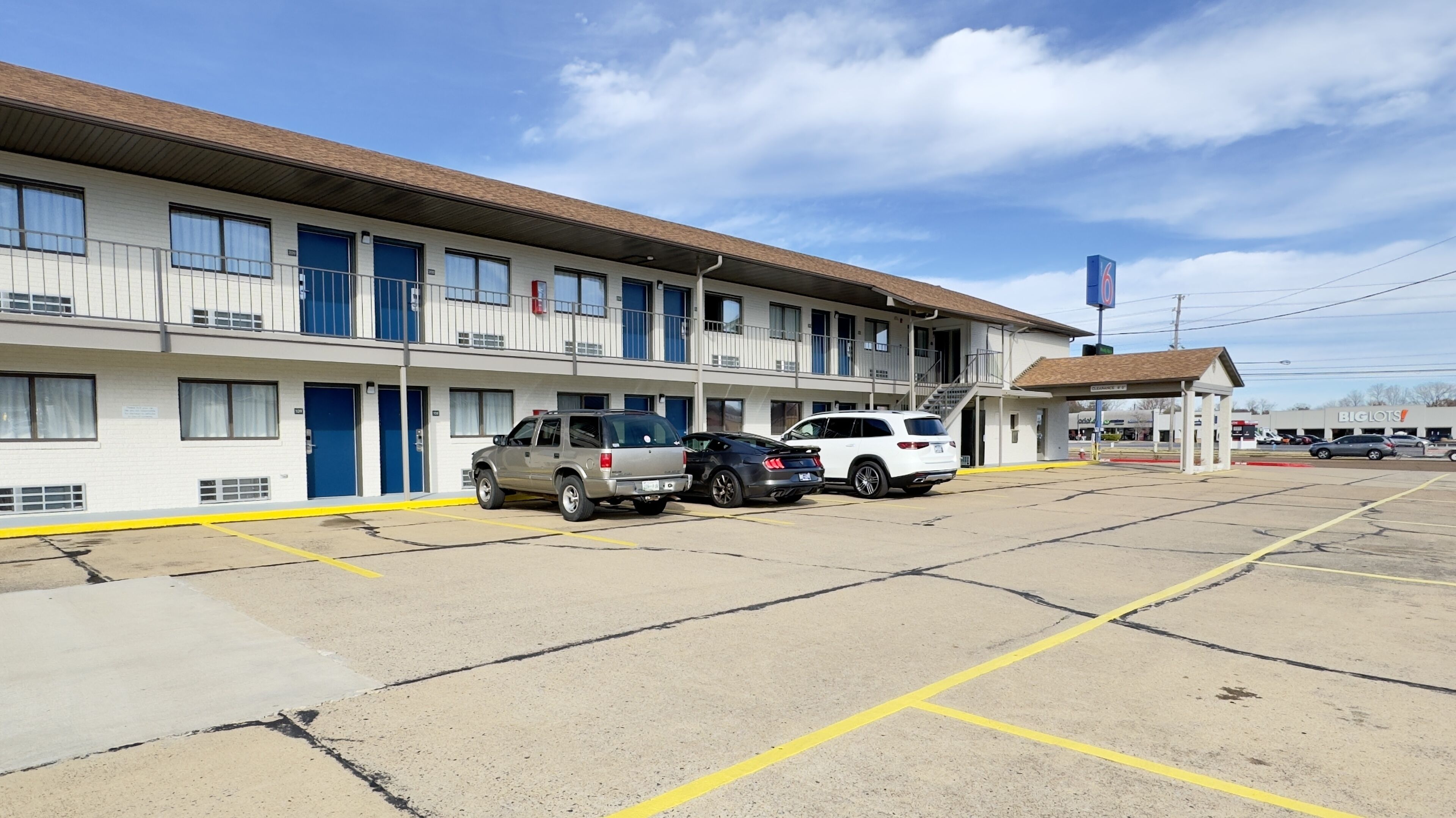 A motel with a row of rooms, a covered parking area, and a Big Lots store in the background.