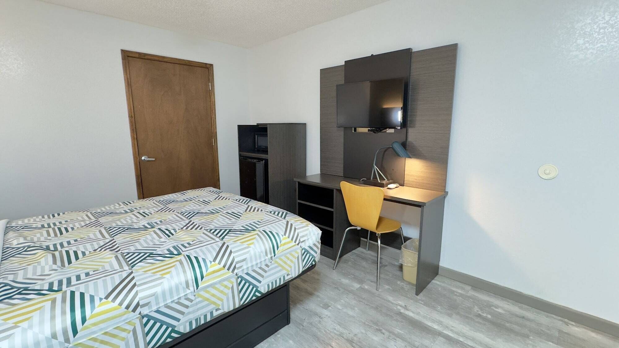 Un dormitorio con cama, escritorio, silla y televisor.