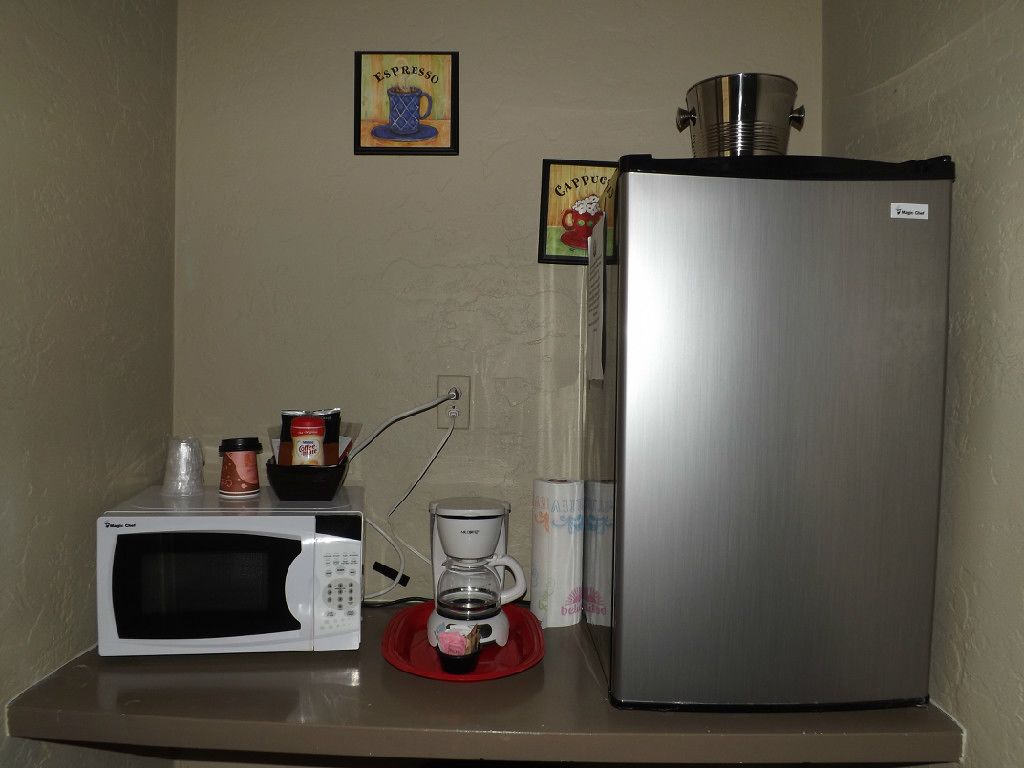 Una kitchenette equipada con microondas, cafetera y refrigerador de acero inoxidable.