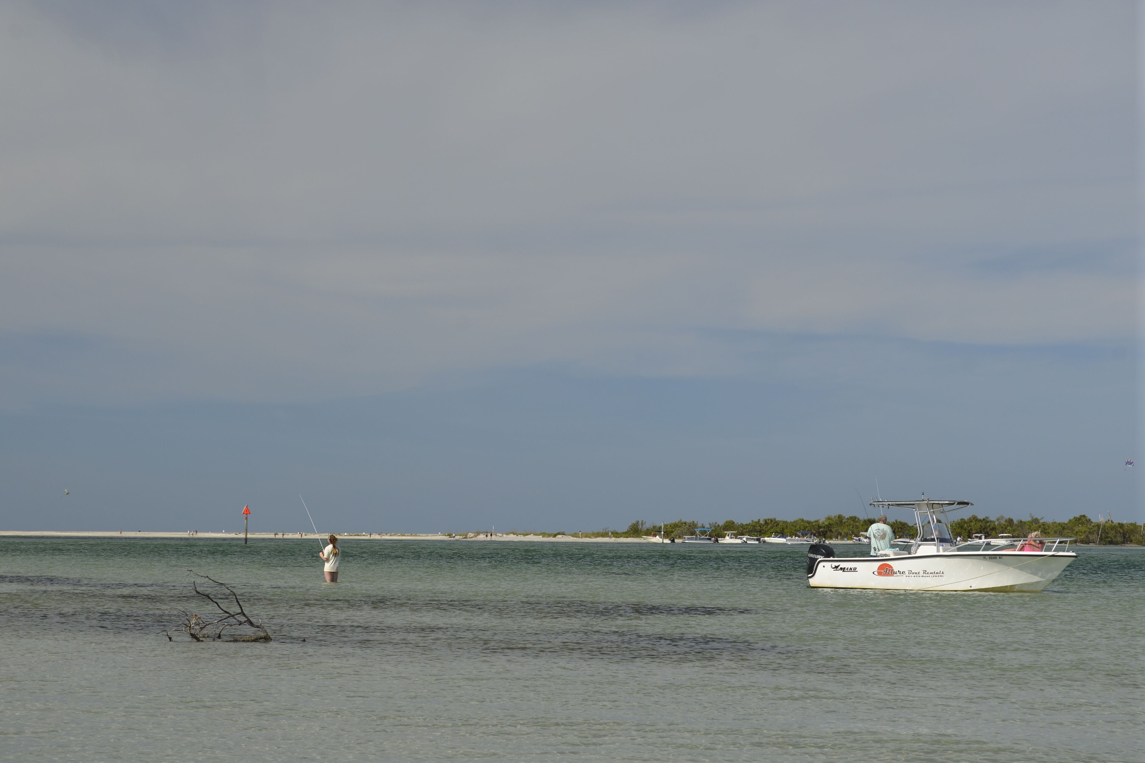 Un bateau sur une eau calme, avec une personne qui pêche à proximité.