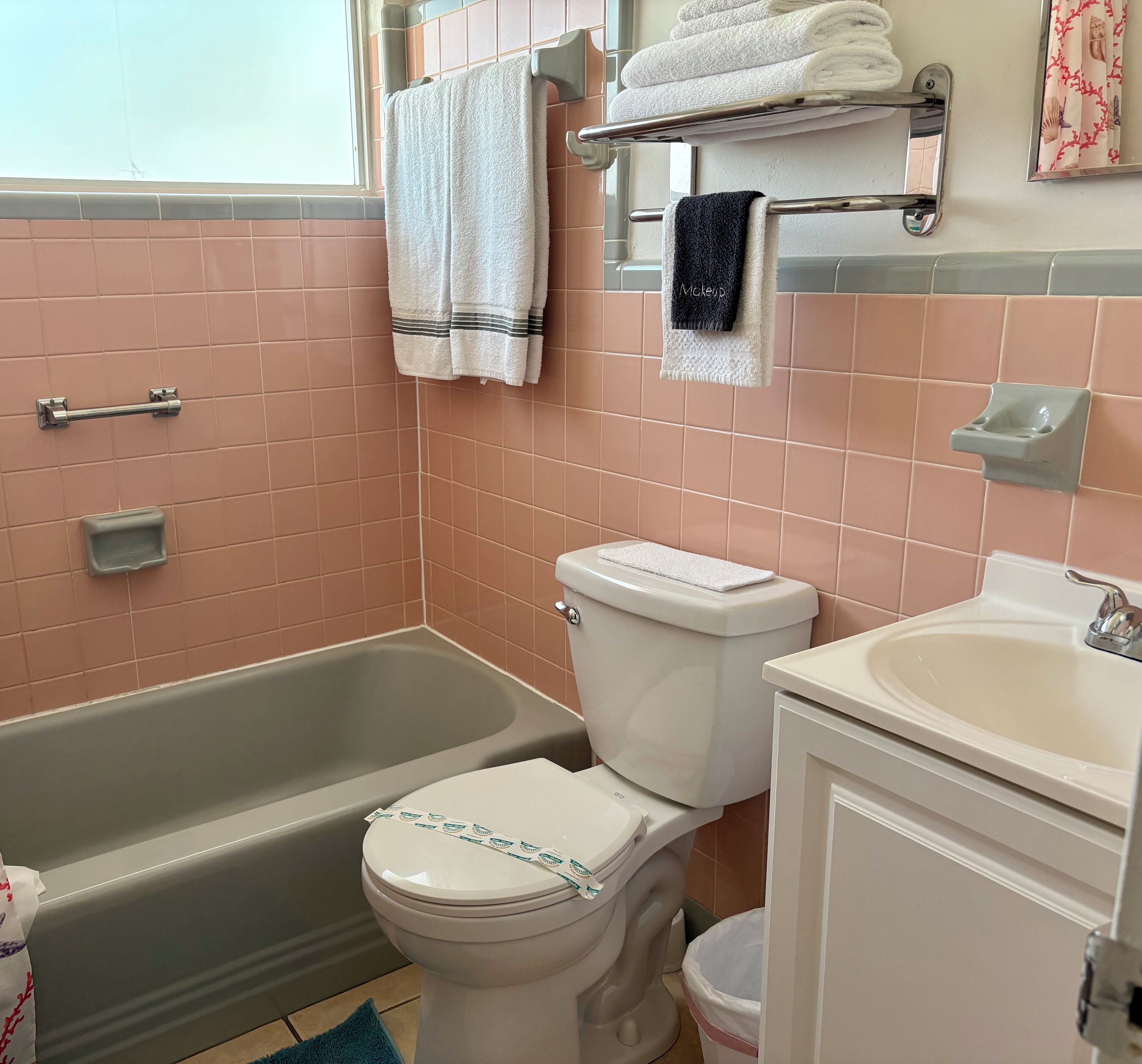 A bathroom with a bathtub, toilet, and sink. There are towels hanging on a rack and a soap dish on the wall.