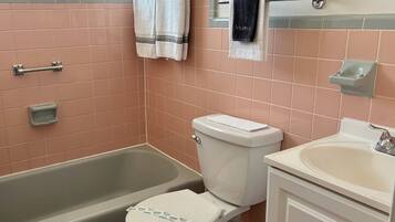 A bathroom with a bathtub, toilet, and sink. There are towels hanging on a rack and a soap dish on the wall.