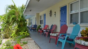 A row of colorful Adirondack chairs outside a building with a blue door and windows. - Sun Life Beach Hotel (Englewood)