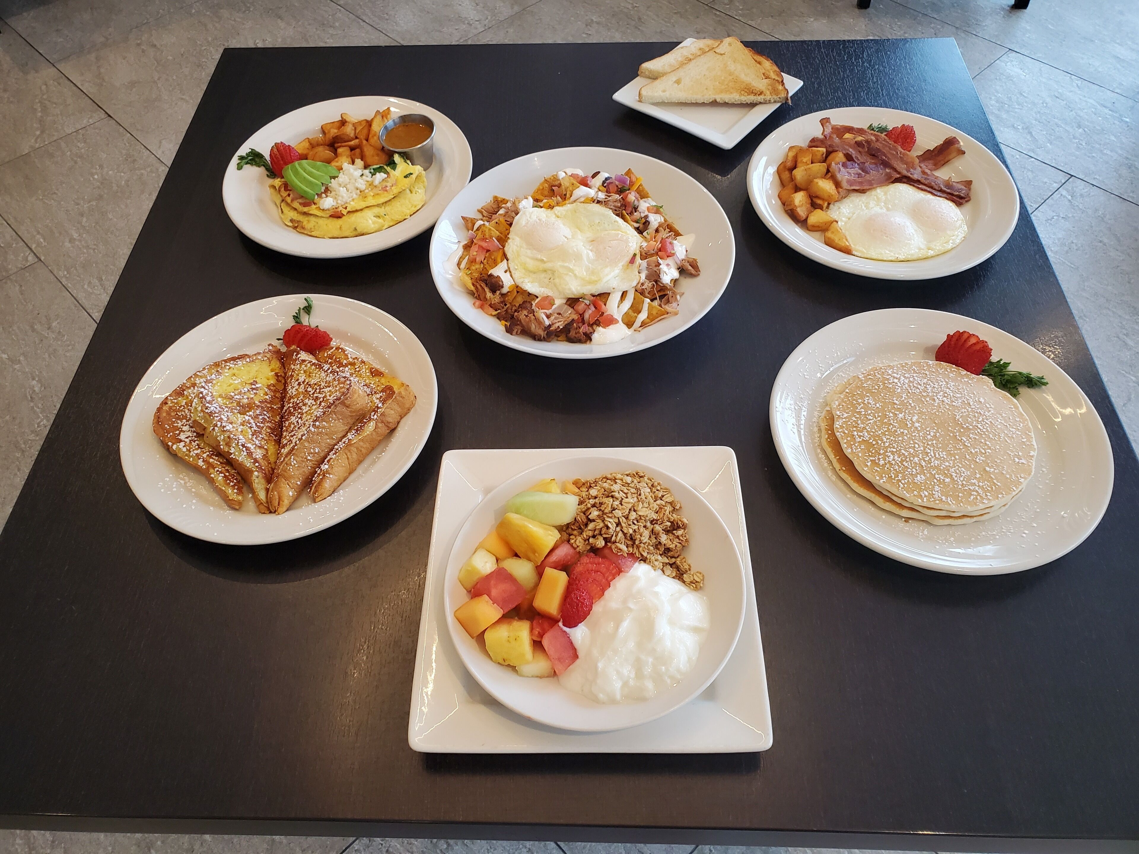 A table with six plates of breakfast food.