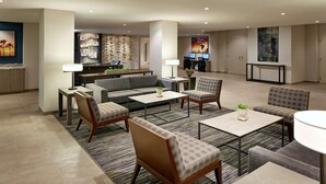 Eine moderne Hotelhalle mit einer Couch, Sesseln, einem Couchtisch und einem Fernseher.