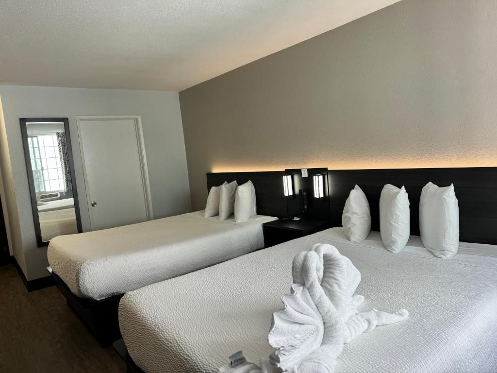 A hotel room with two beds, a nightstand, and a mirror.