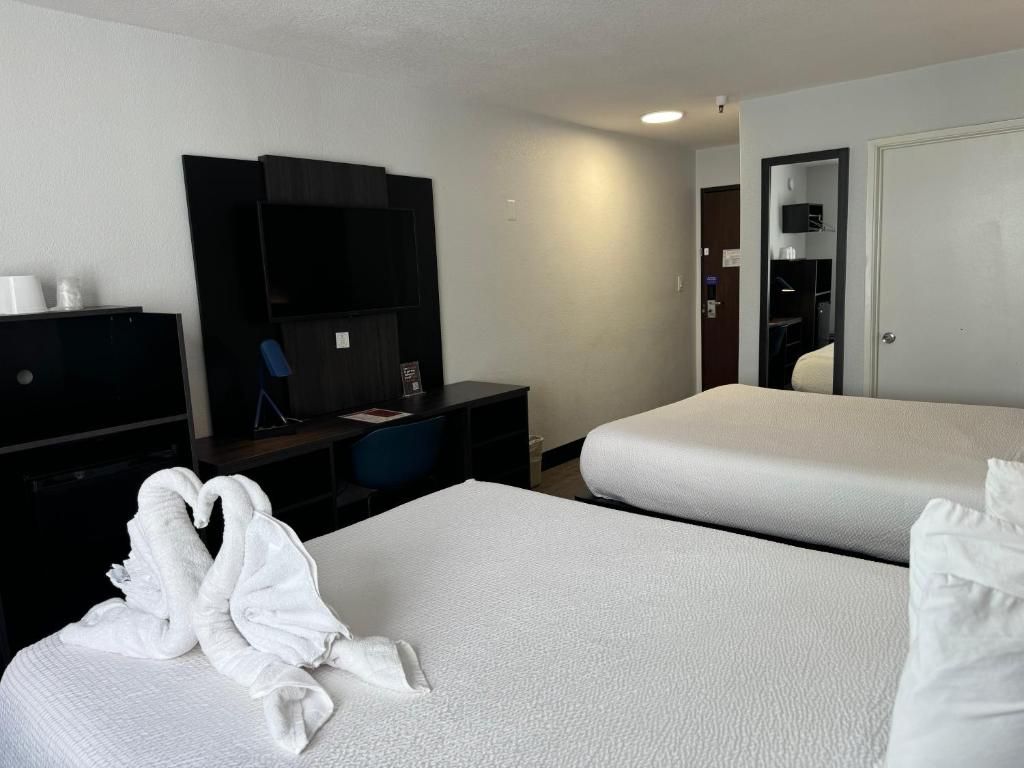 Une chambre d’hôtel avec deux lits, un bureau, une télévision et une armoire.