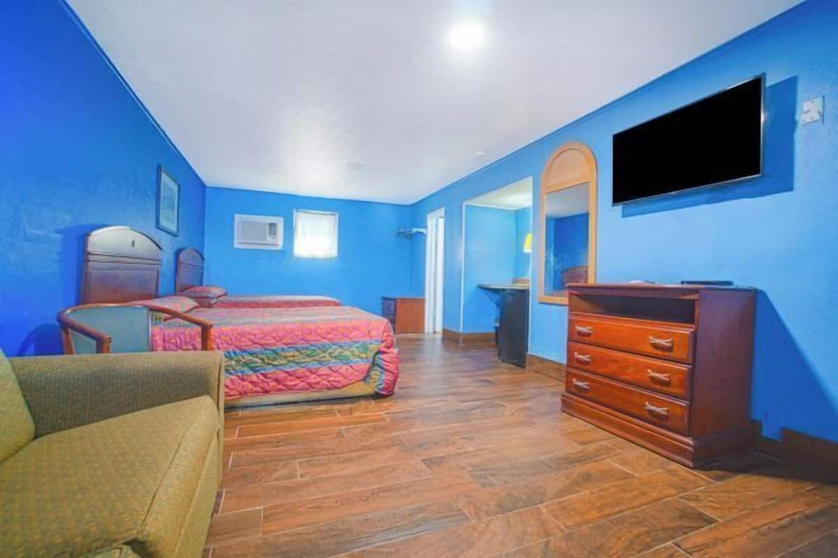 A bedroom with a bed, a dresser, a TV, and a mirror.