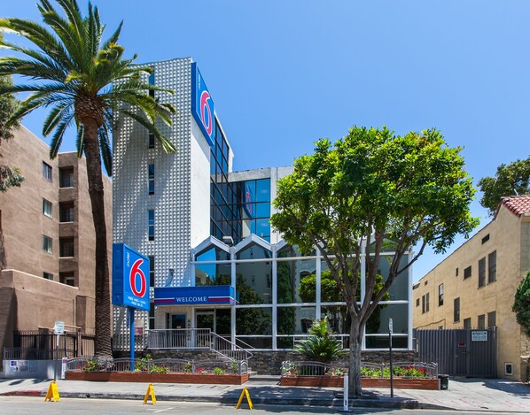 A modern building with a prominent '6' sign, a welcoming entrance, and a landscaped area with trees and plants.