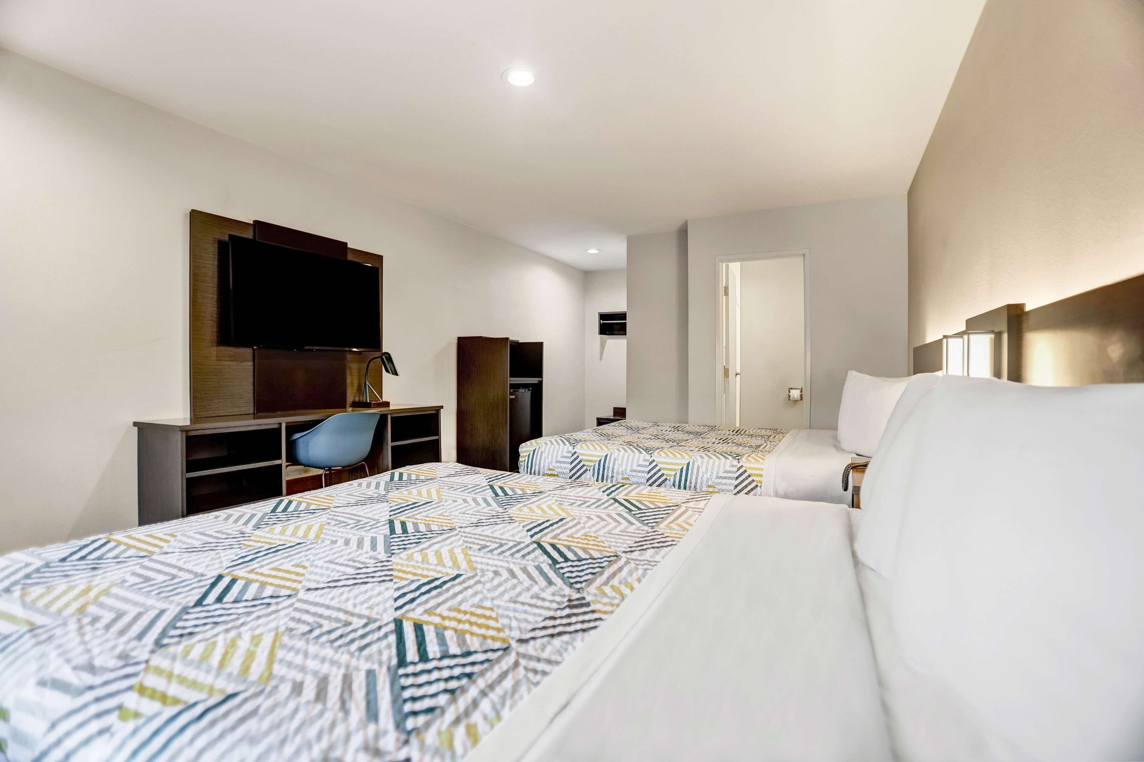 Une chambre d’hôtel avec deux lits, une télévision, un bureau et une chaise.