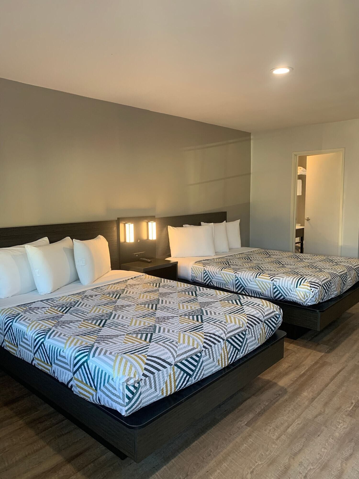 Une chambre d’hôtel avec deux lits, chacun agrémenté de draps à motifs, une table de chevet et un luminaire fixé au mur.