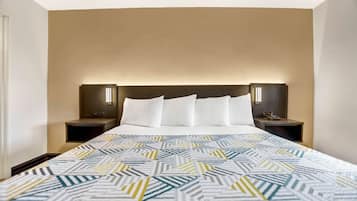 A hotel room with a large bed, two bedside tables, and a headboard with integrated lighting.