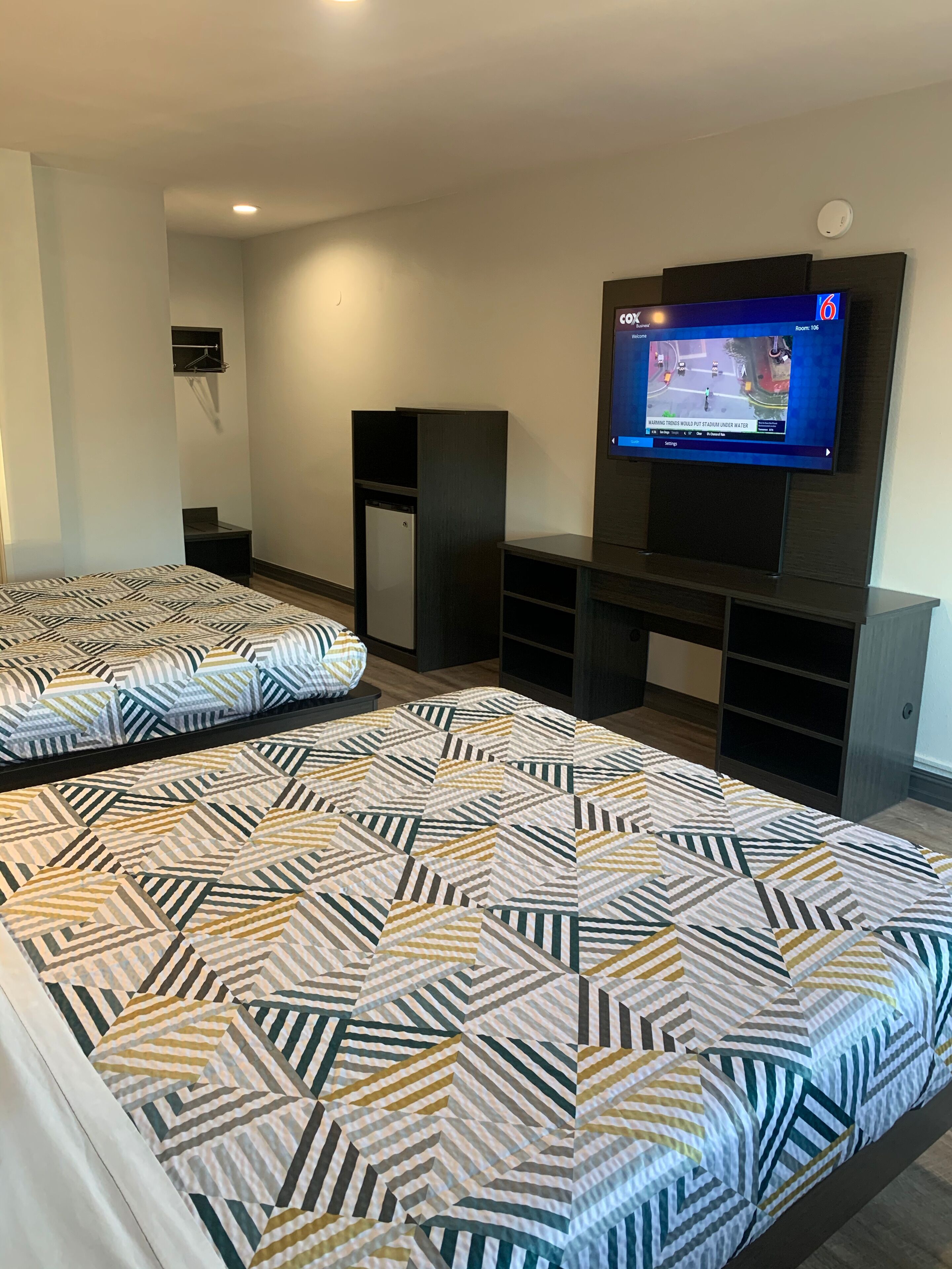 A modern hotel room with a large bed, a TV mounted on the wall, and built-in storage units.