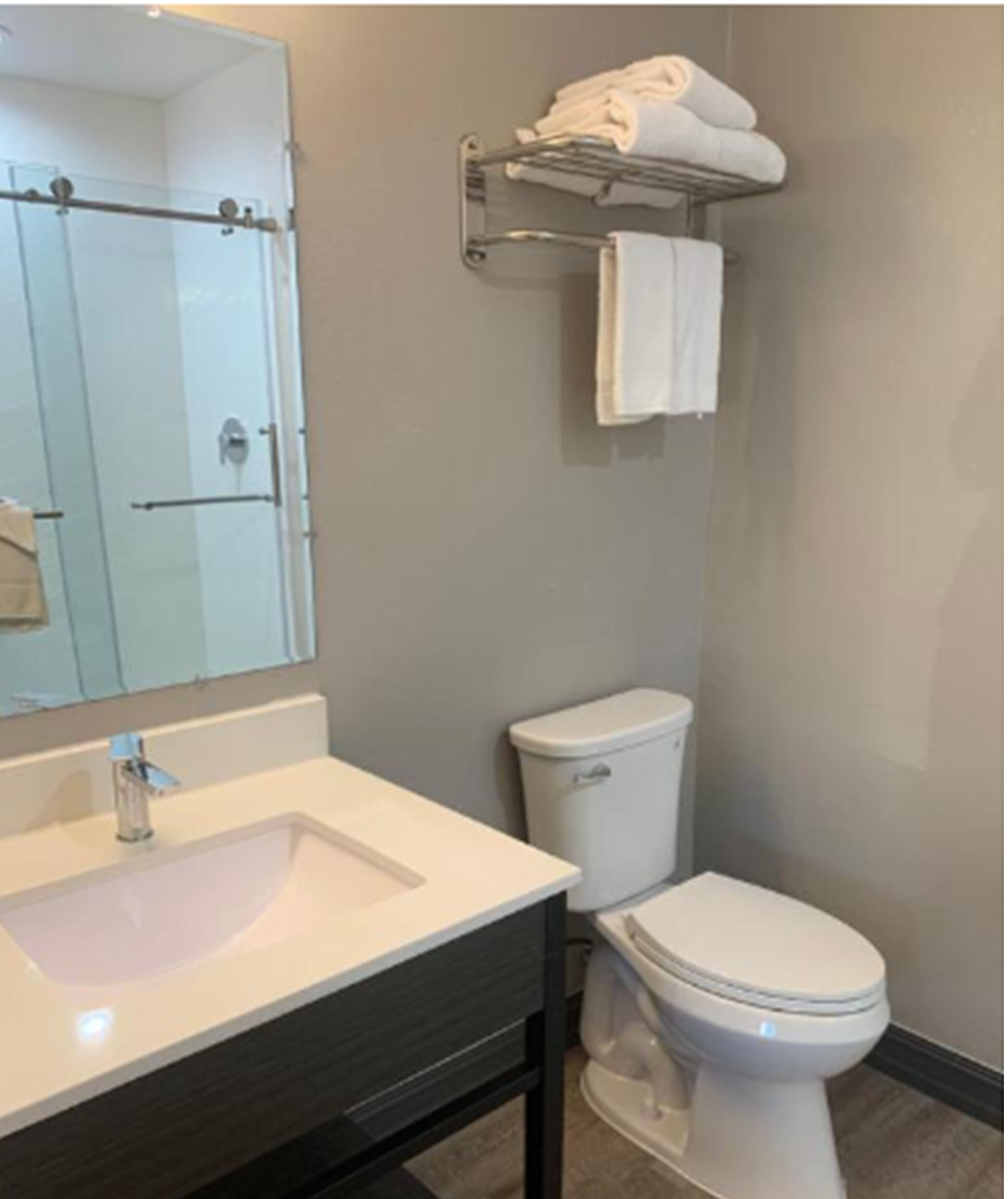 A bathroom with a sink, toilet, and a glass shower enclosure.