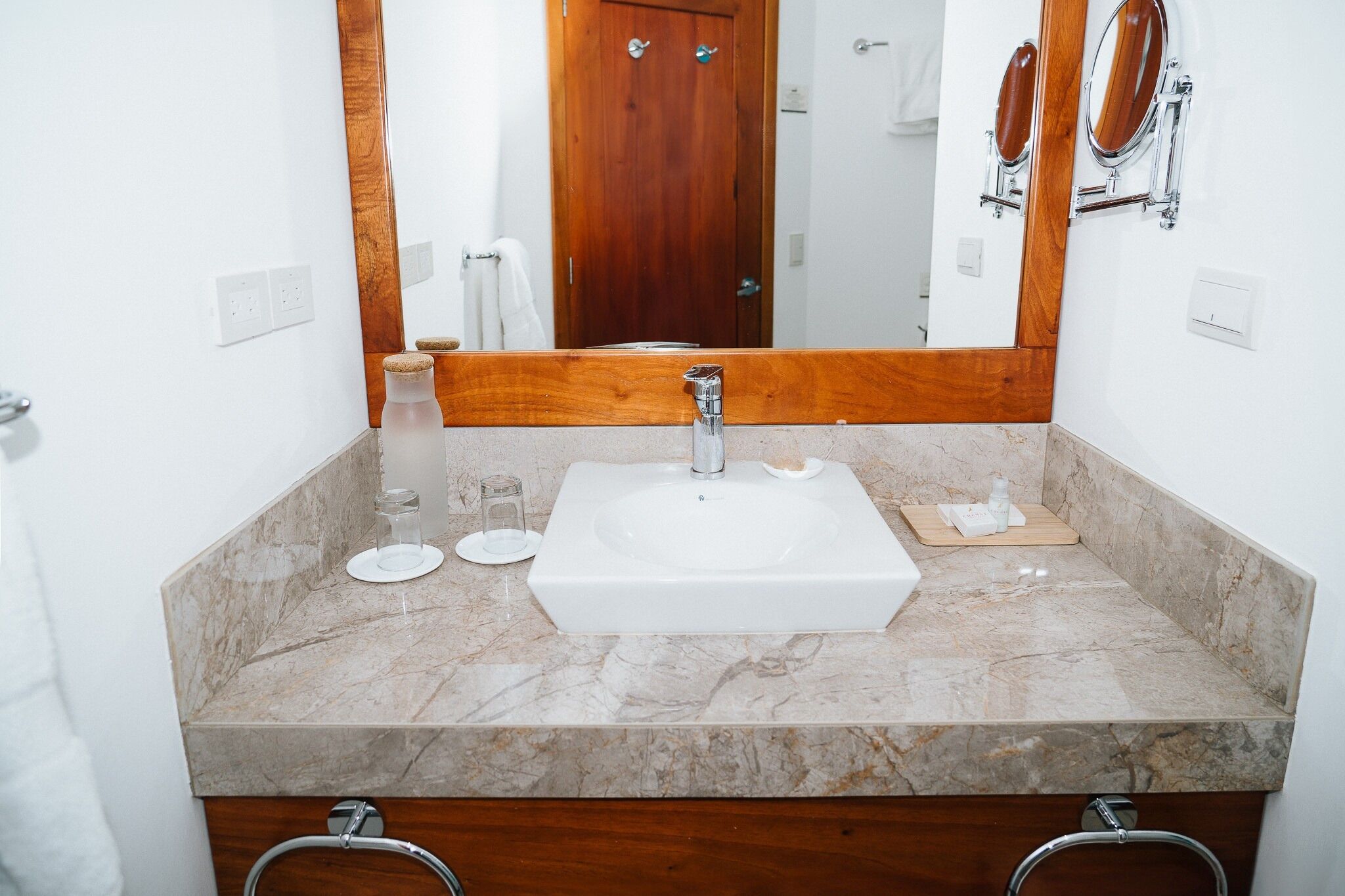 A bathroom with a white sink, a mirror, and a wooden door in the background.