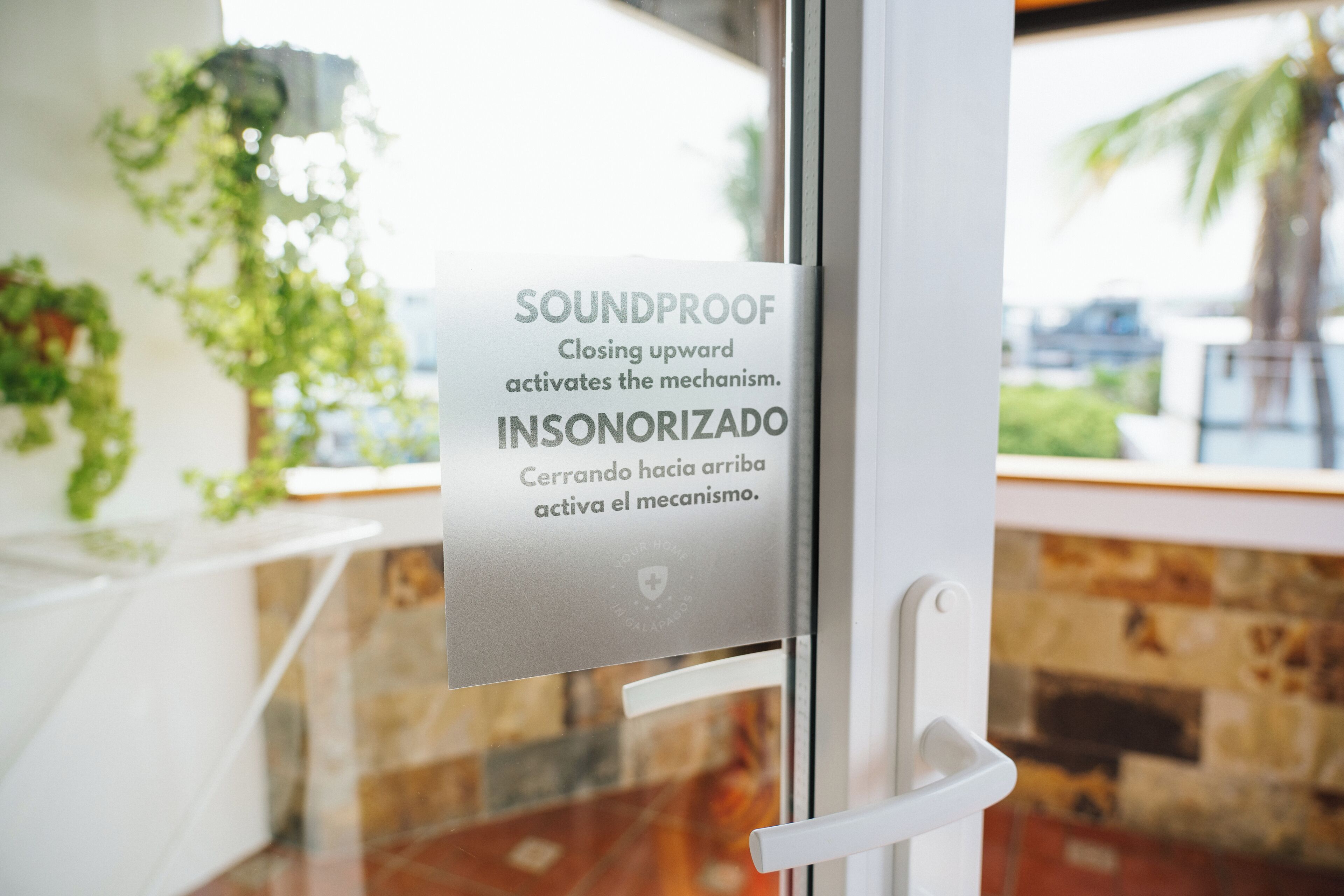 A glass door with a sign indicating a soundproof feature and a mechanism that is activated by closing upward.