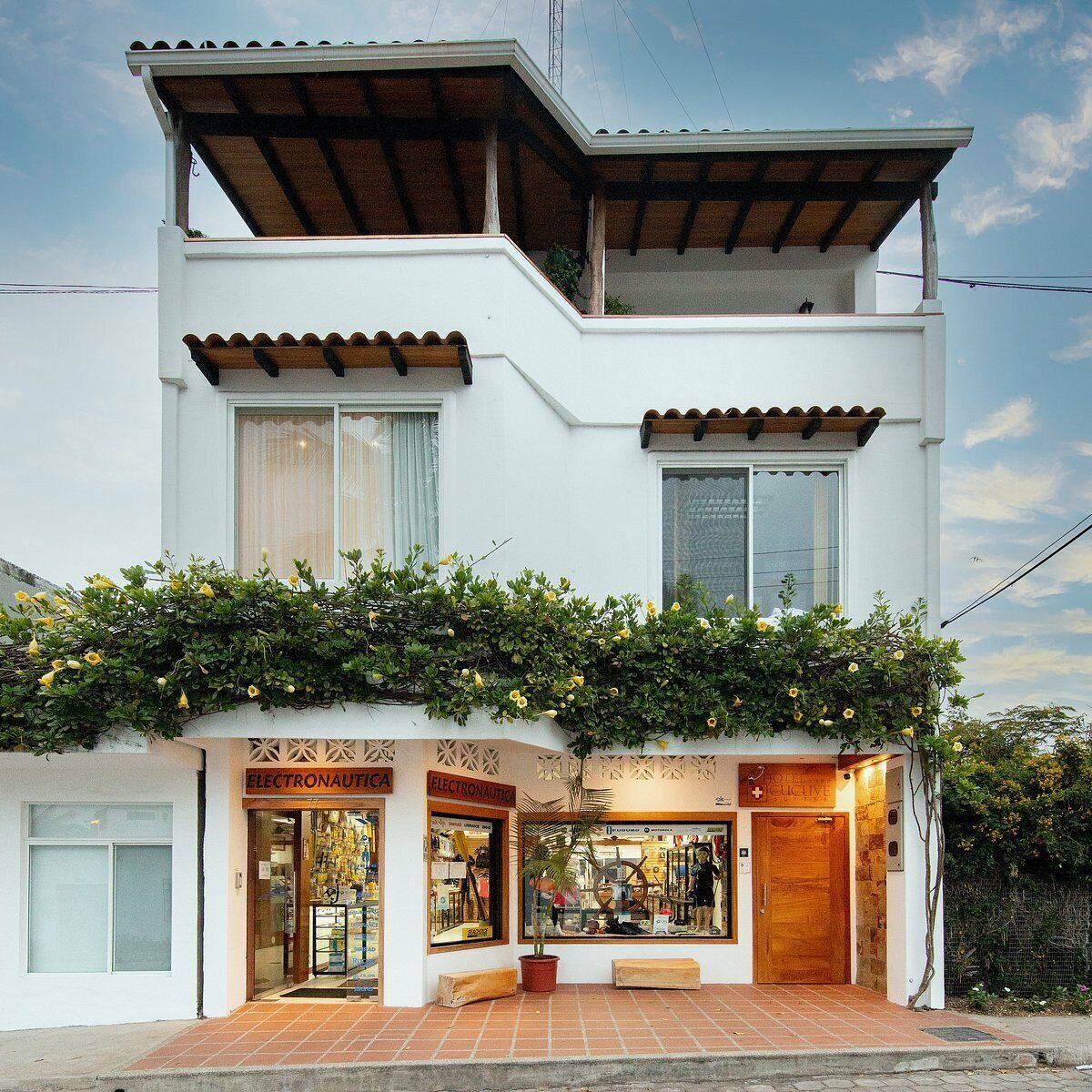 A two-story building with a white facade, a covered entrance, and a shop on the ground floor.