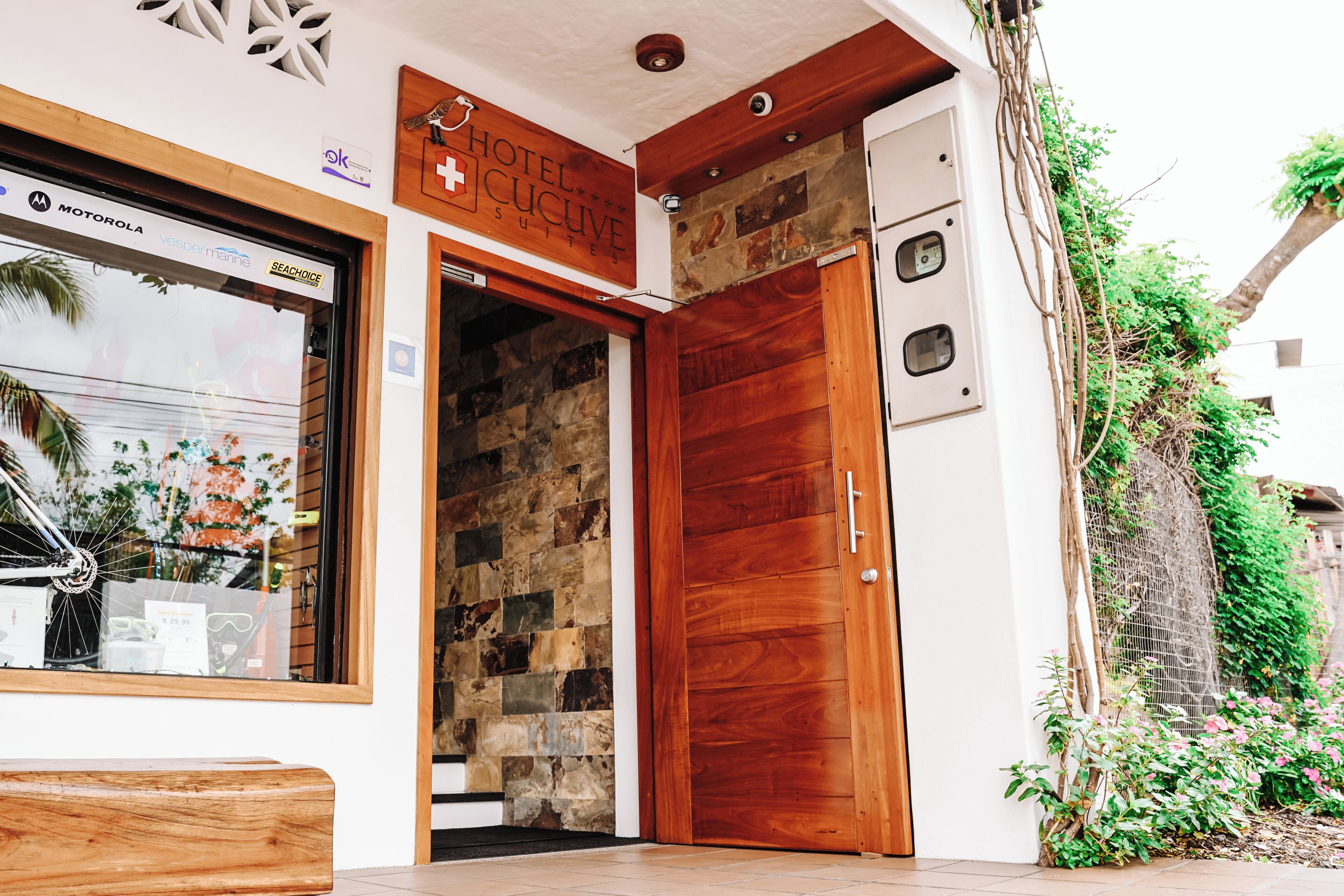 Entrada de hotel con puerta de madera, pared de piedra y un cartel sobre la puerta.