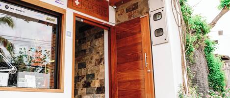 Entrada de hotel con puerta de madera, pared de piedra y un cartel sobre la puerta.