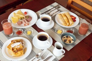 Une table mise pour le petit-déjeuner, avec des assiettes remplies de nourriture, des tasses de café et une carafe de lait.
