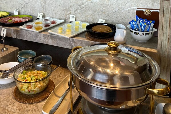 A buffet with various food items, including a large pot of soup, bowls of salad, and containers of condiments. - Hotel Cucuve (Puerto Ayora)