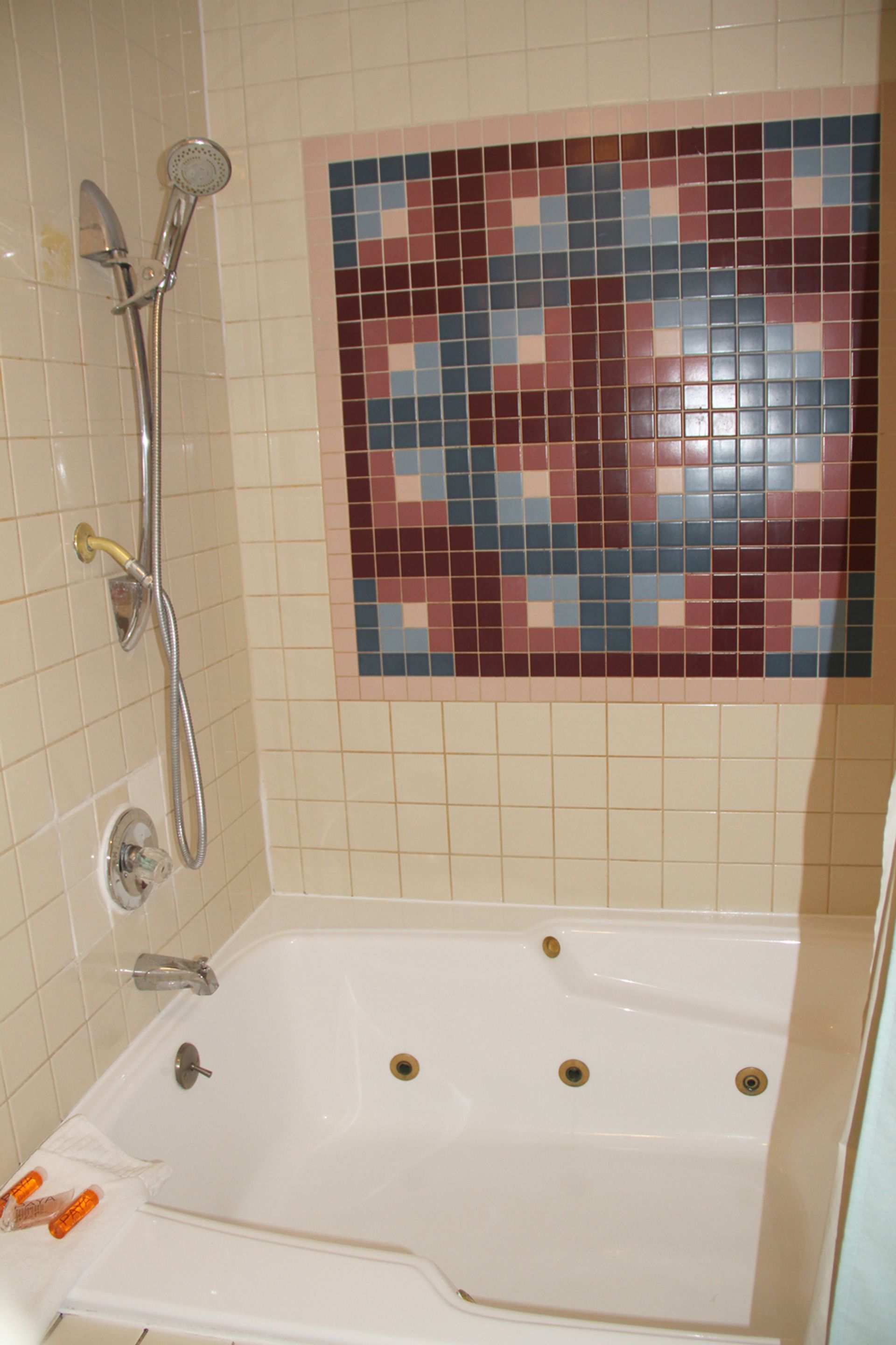 A bathroom with a bathtub, a shower, and a mosaic tile wall.