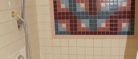 A bathroom with a bathtub, a shower, and a mosaic tile wall.