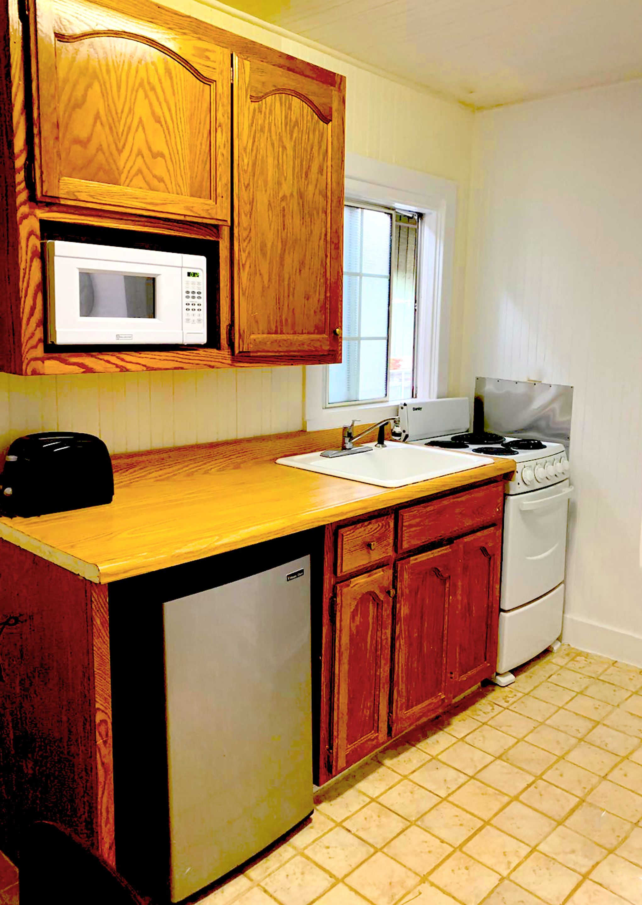 A kitchen with wooden cabinets, a microwave, a sink, a stove, and a dishwasher.