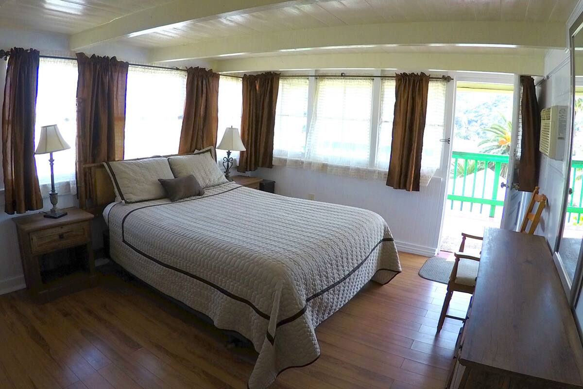 A bedroom with a bed, bedside tables, a desk, and curtains.