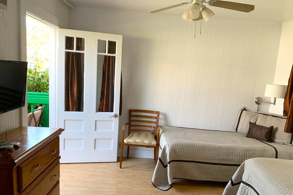 A bedroom with a bed, a chair, a TV, and a ceiling fan.