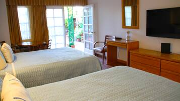 Habitación de hotel con dos camas, un escritorio, una silla, un televisor y vistas al exterior.
