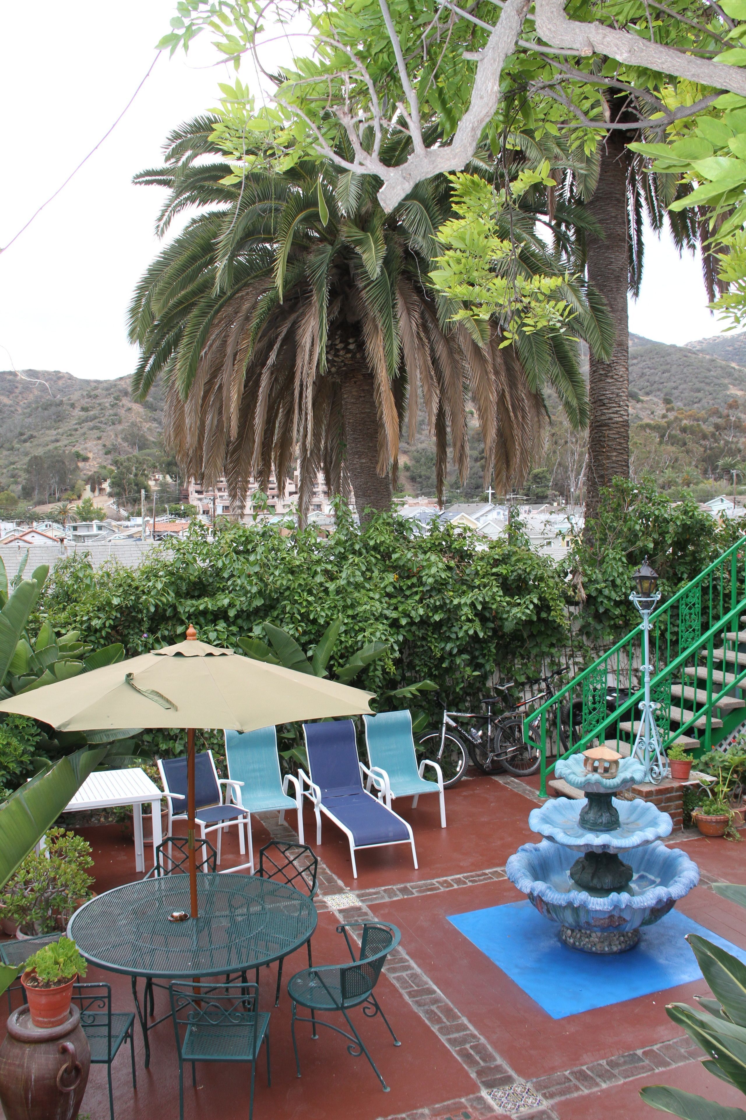 A patio with a round table, chairs, a fountain, and a staircase.