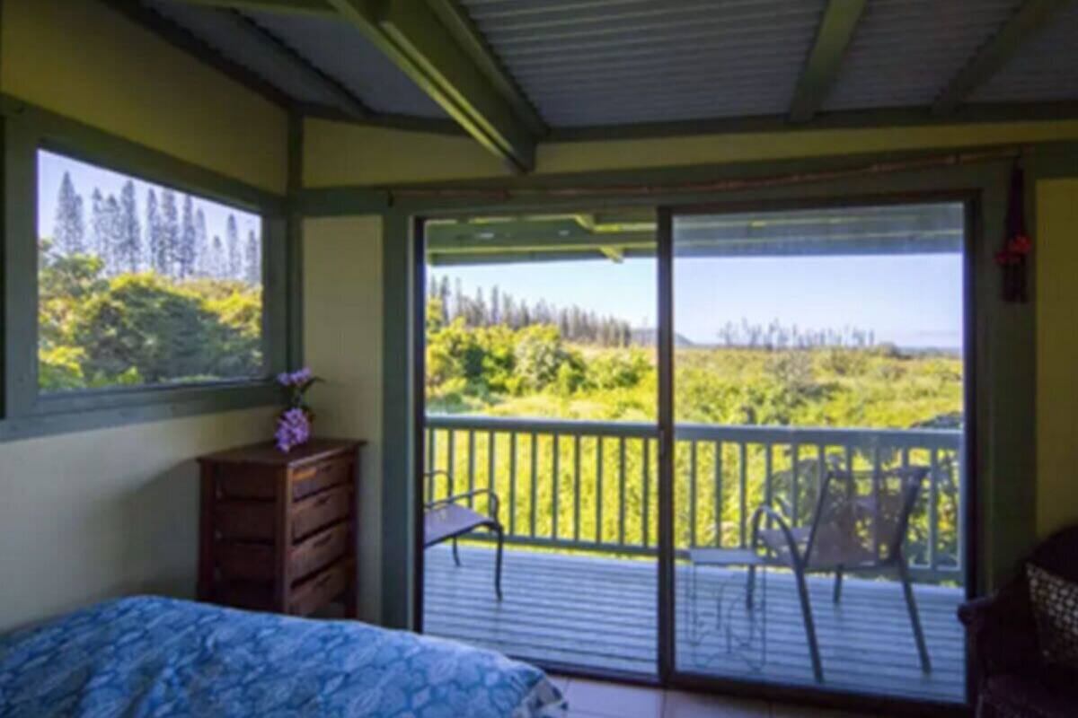 Une chambre à coucher comprenant un lit, une commode et un balcon donnant sur un espace verdoyant.